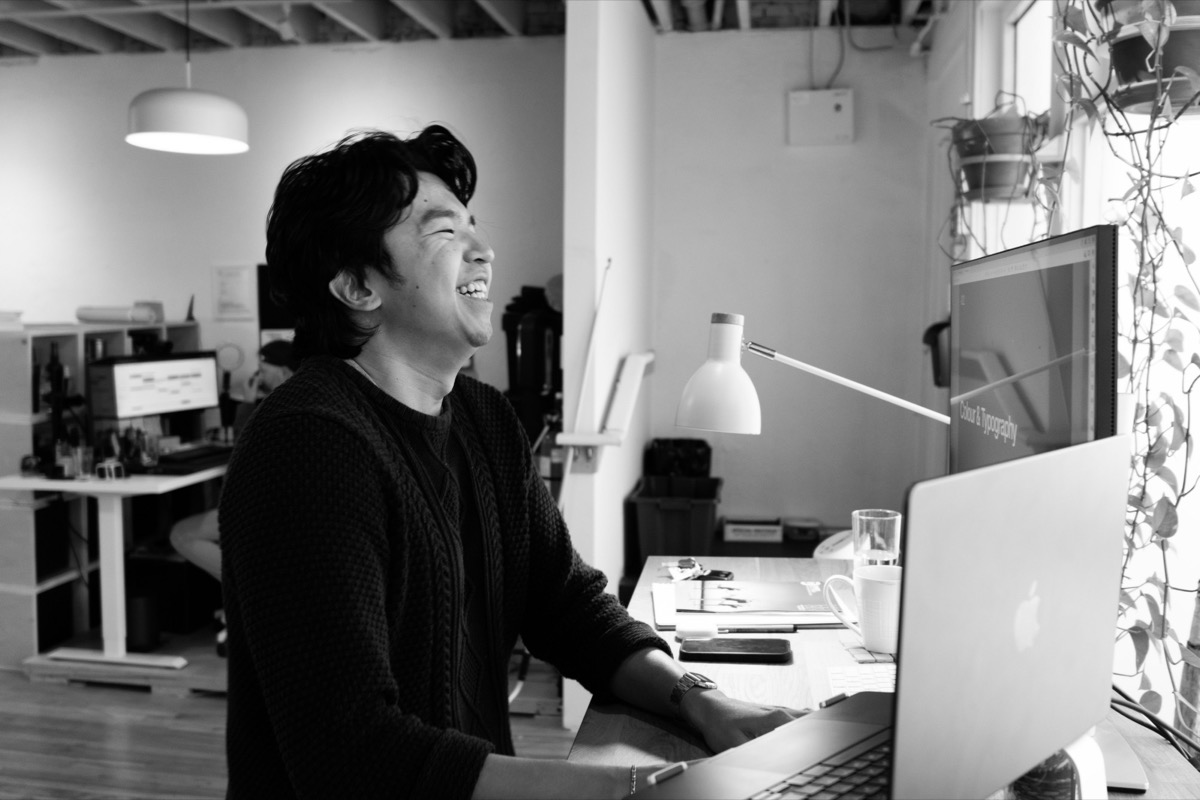 A designer at Becoming at his desk, a brand guide open on screen behind him